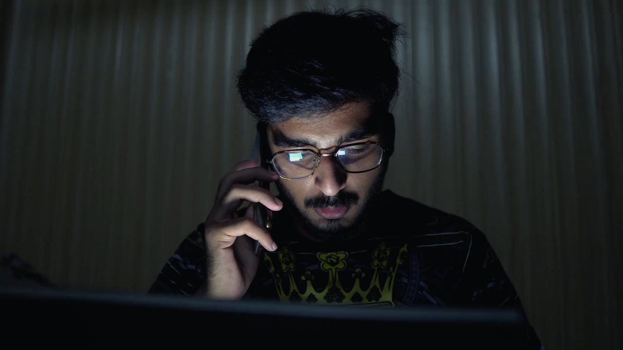 A man on a call at his desk late in the evening